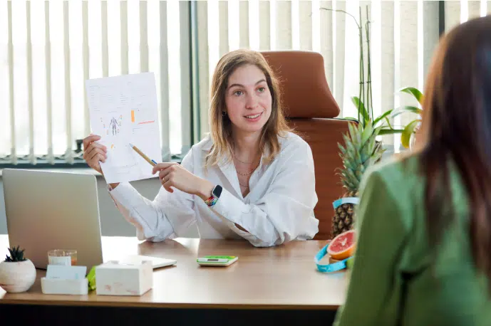 Participate in the BetterTogether weight loss challenge with friends: Office discussion on healthy eating with a laptop, pineapple, and sliced fruit.